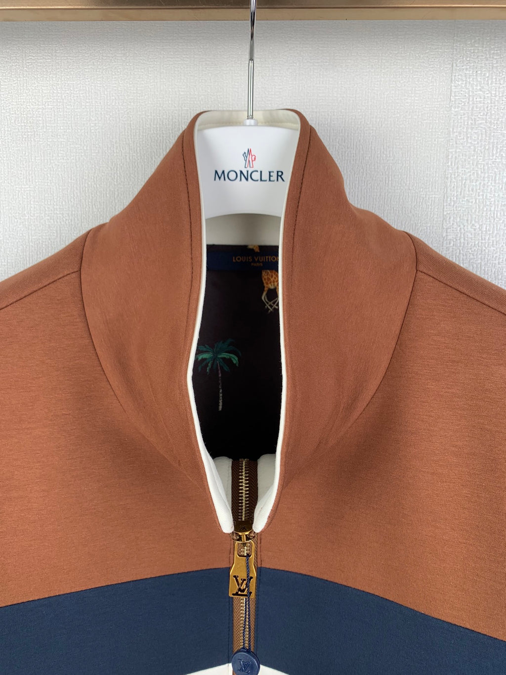 Brown zip-up jacket open at neck, showing black lining and gold zipper hardware