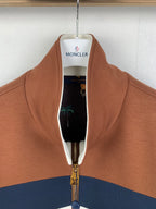 Brown zip-up jacket open at neck, showing black lining and gold zipper hardware