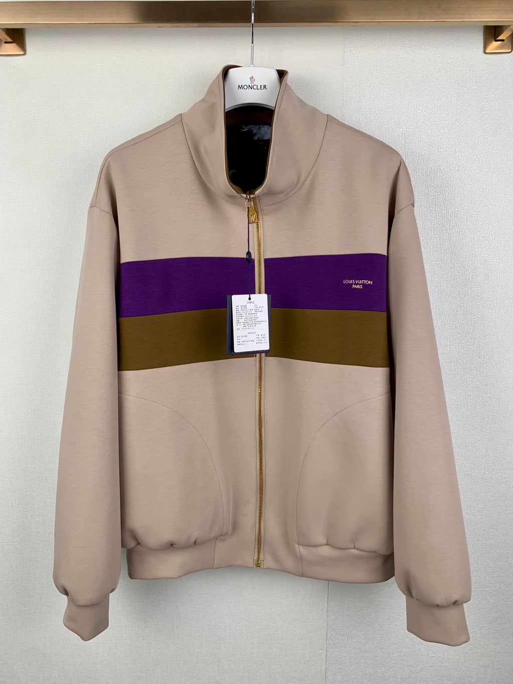 Beige zip-up jacket with purple and olive horizontal stripe, stand collar and pockets