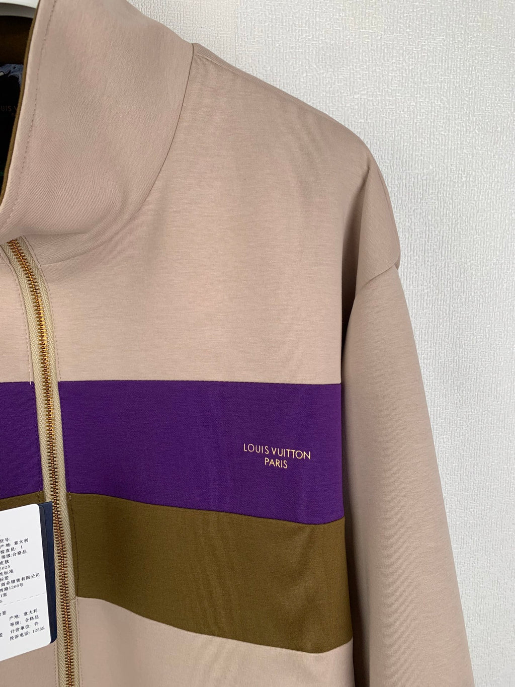 Beige zip-up jacket with purple and olive stripe and small chest logo text