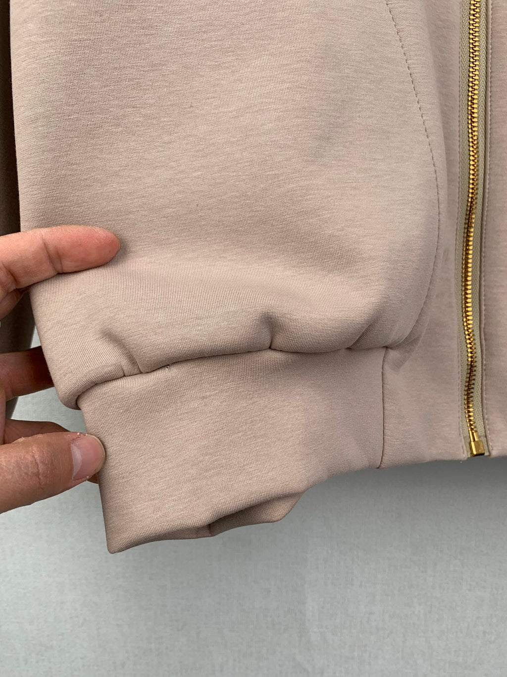 Beige jacket lower hem with stitched seam and elastic gather near pocket