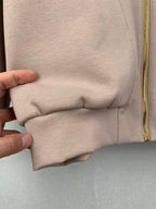 Beige jacket lower hem with stitched seam and elastic gather near pocket