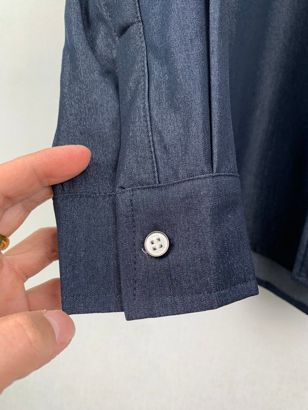 Dark blue shirt cuff close-up with single button detail