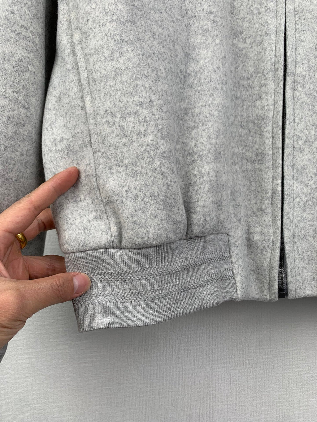 Grey zip-up jacket sleeve cuff and front pocket seam detail