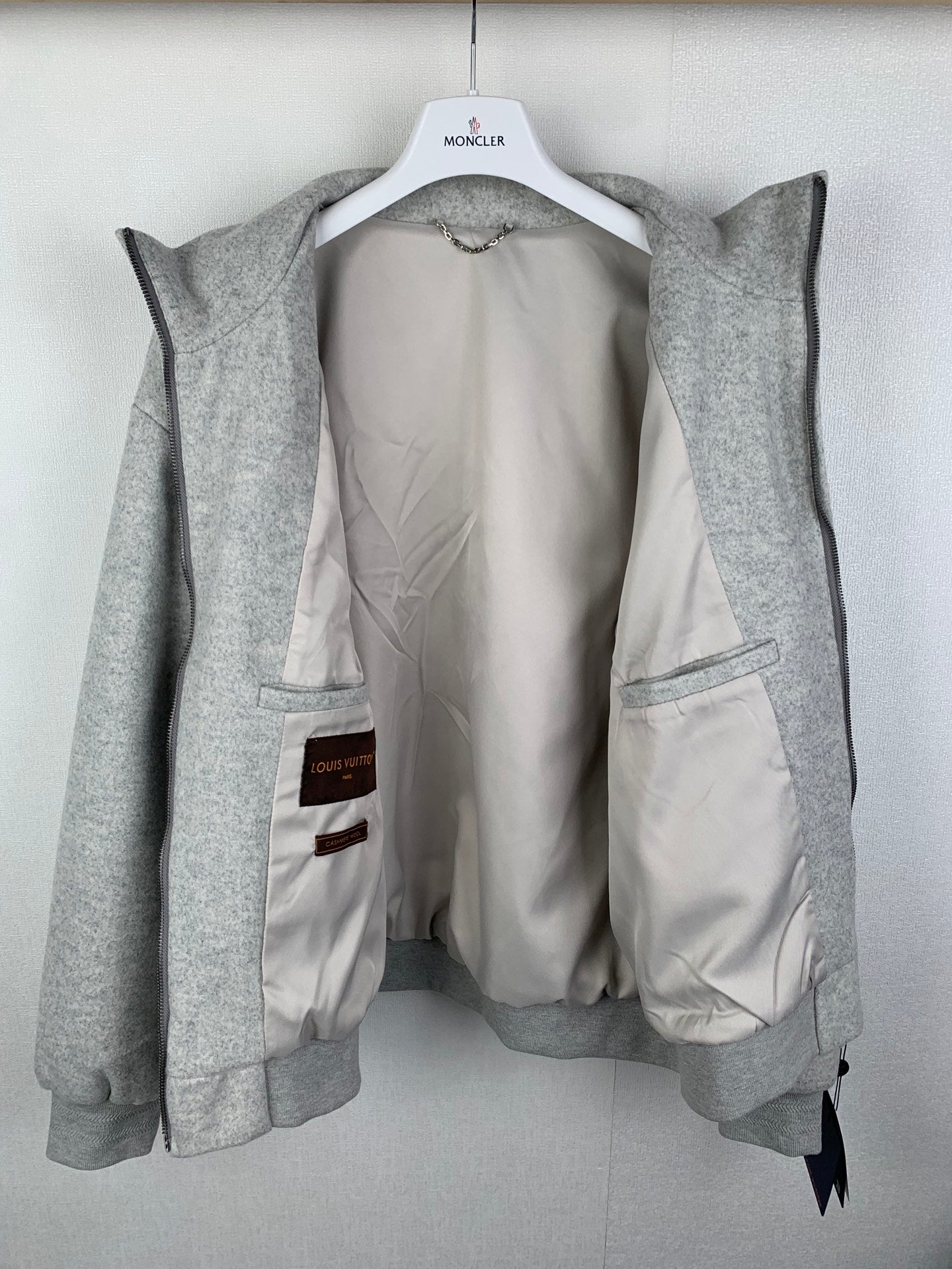 Grey zip-up jacket opened to show light inner lining and zippered pocket