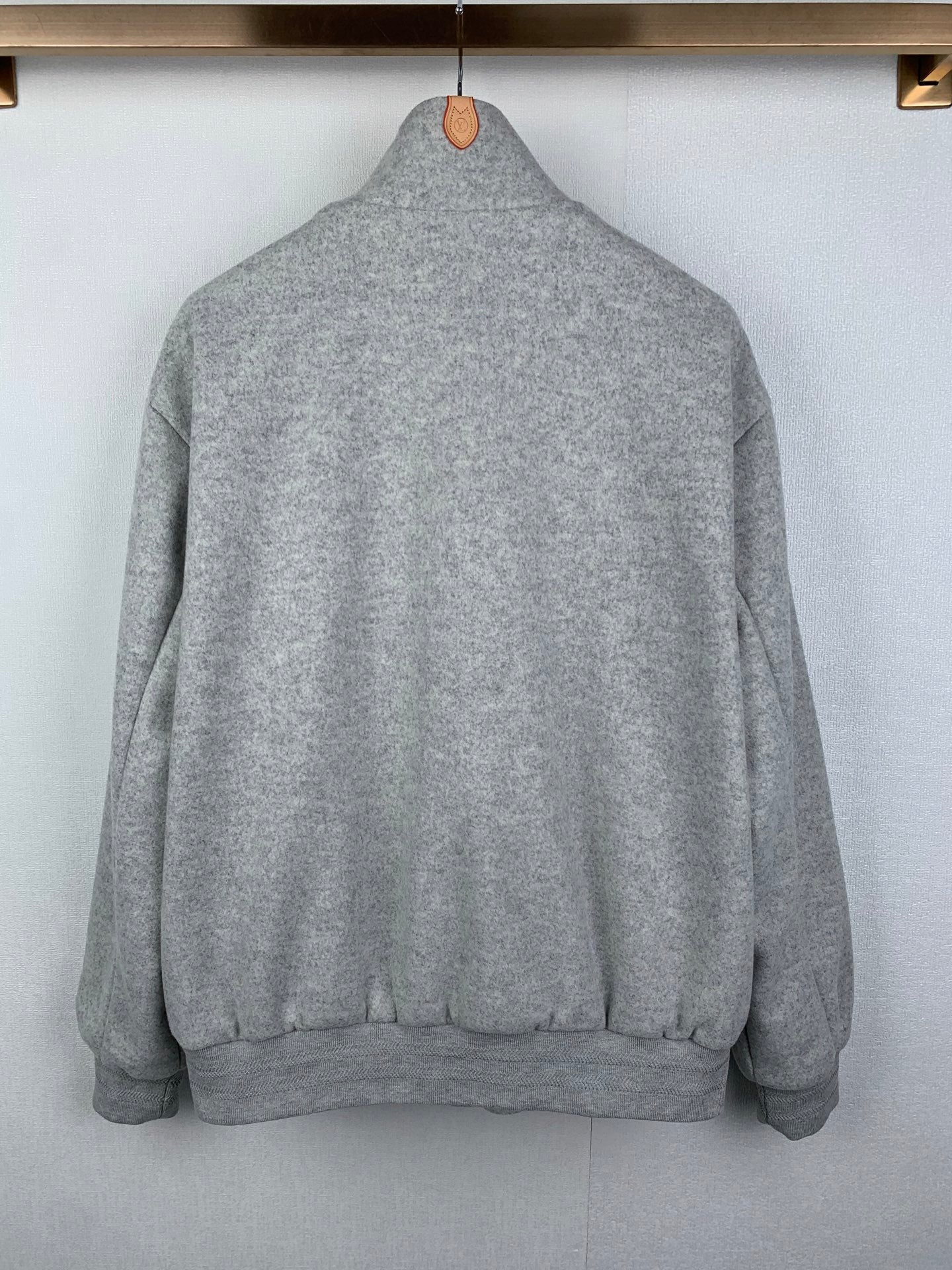 Grey zip-up jacket with ribbed hem and cuffs, back view on hanger