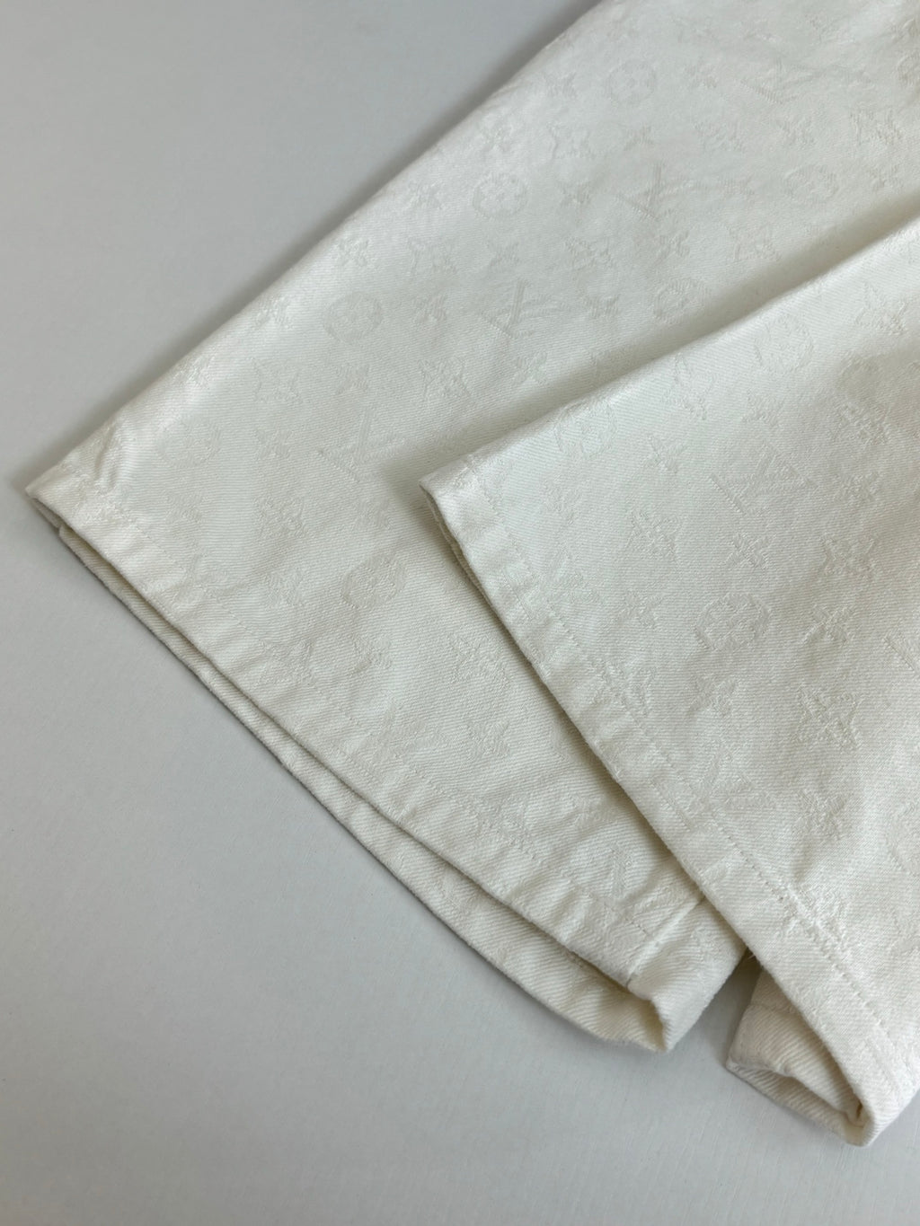 White denim shorts folded flat, visible hem and side seam