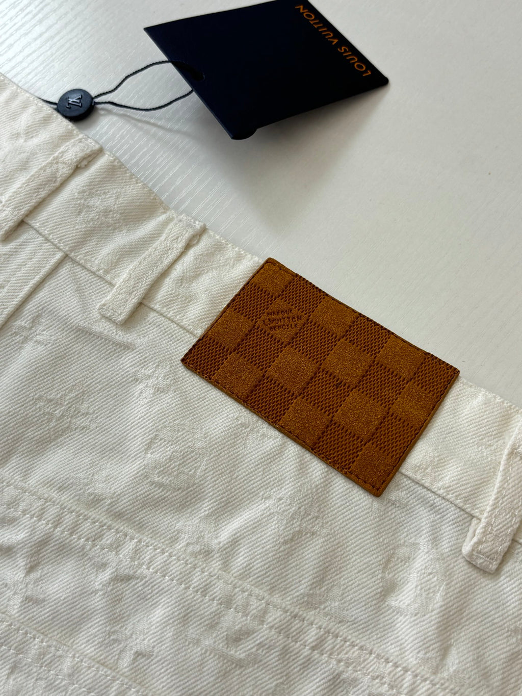 White denim shorts close-up, label tags and check-pattern pocket patch