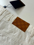 White denim shorts close-up, label tags and check-pattern pocket patch