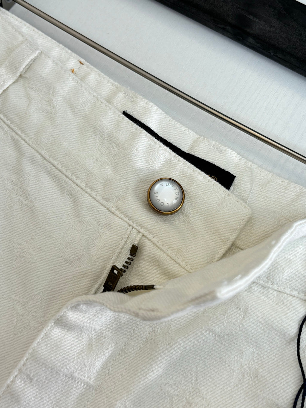 White denim shorts close-up, waistband button and small interior detail