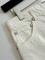 White denim shorts front close-up, metal buttons and waistband hardware