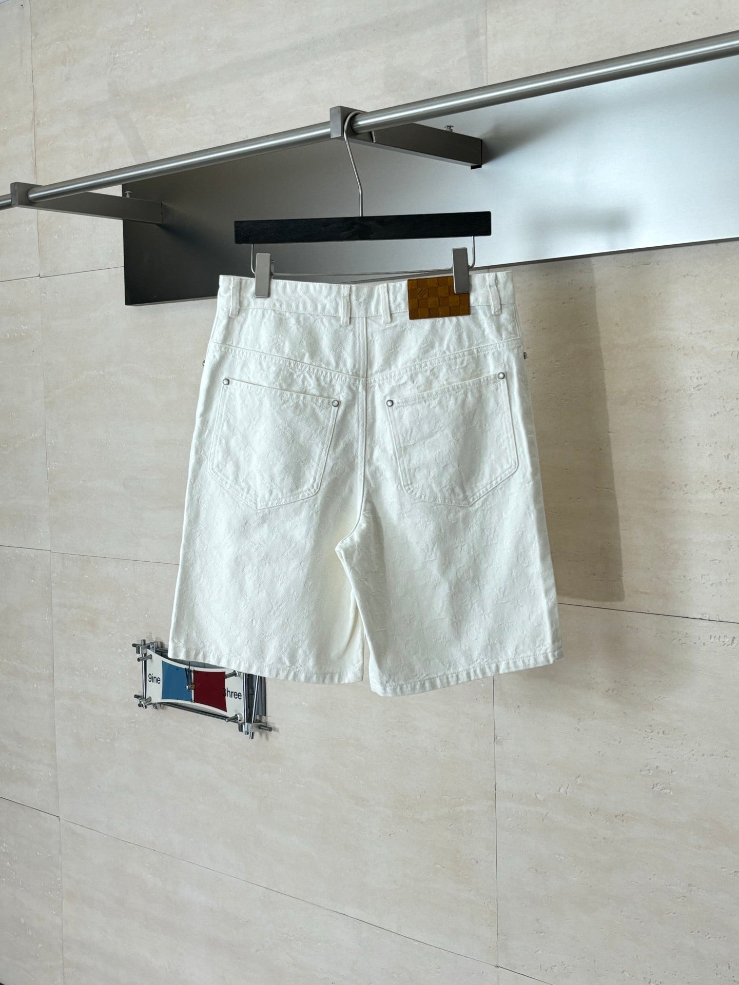 White denim shorts on hanger, front pockets and belt loops with hanging tag