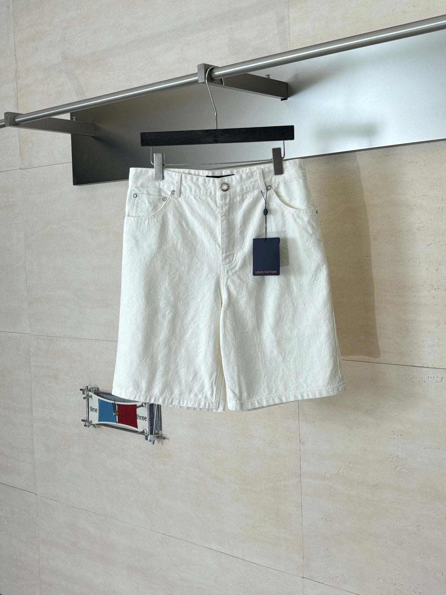 White denim shorts on hanger, elastic waistband and front button closure