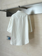 White short-sleeve button-up shirt, back view on a hanging rack