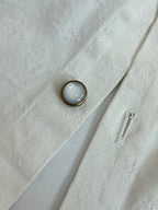 White button-up shirt close-up of metal button on textured fabric