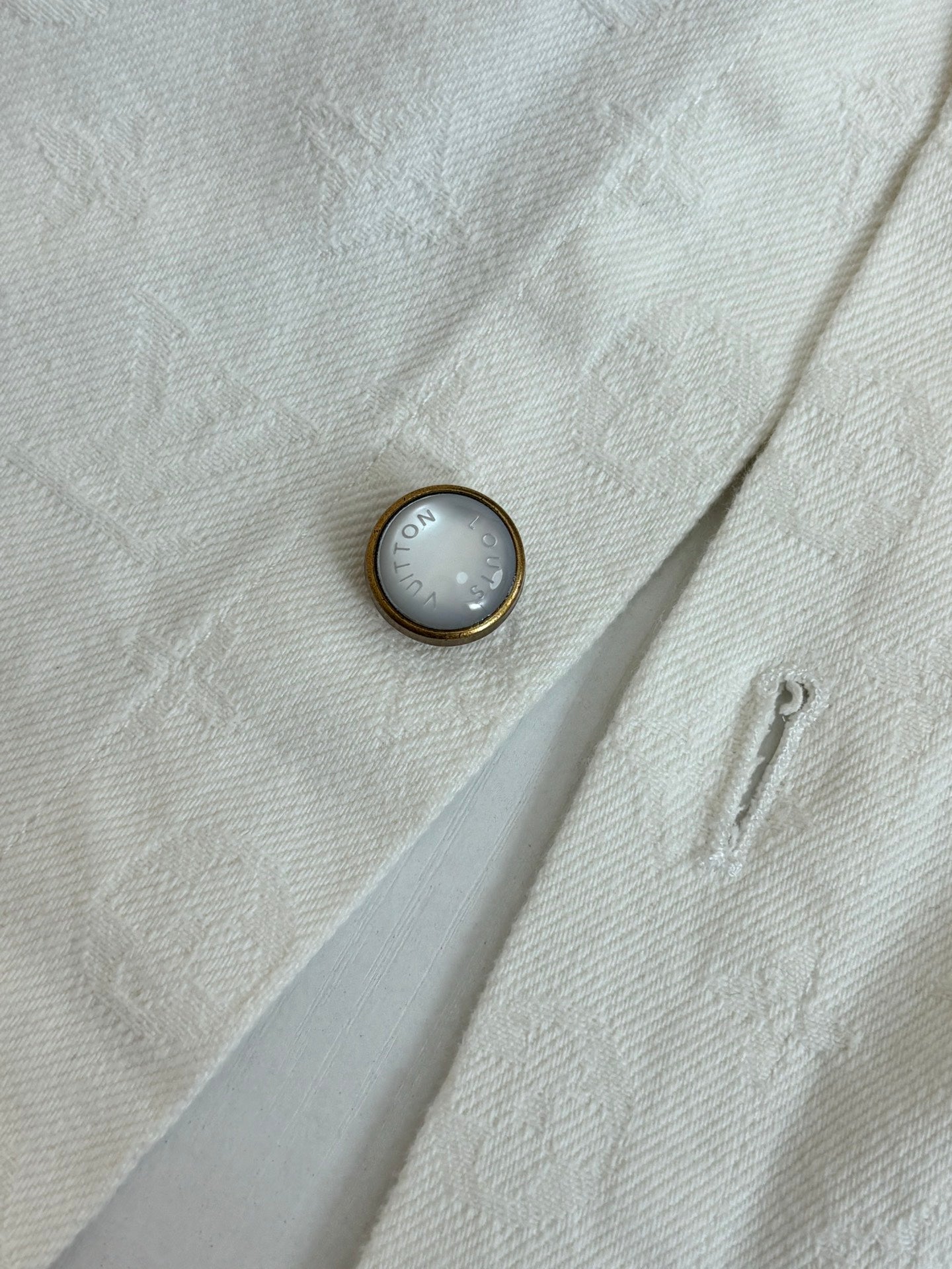 White button-up shirt close-up of metal button on textured fabric