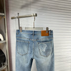 Light-blue denim jeans on hanger with embroidered back pocket artwork