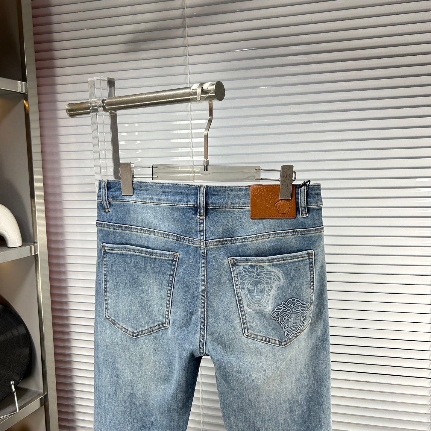 Light-blue denim jeans on hanger with embroidered back pocket artwork