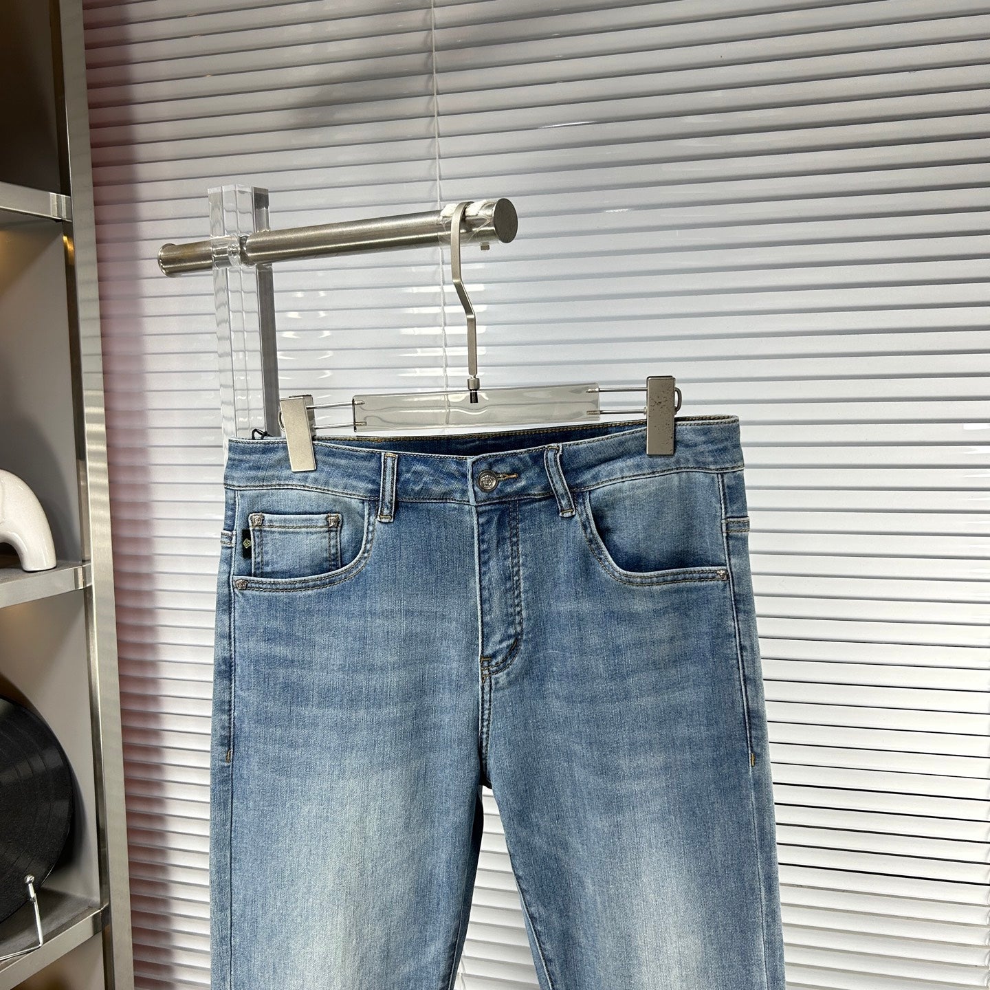 Light-blue denim jeans on hanger with front pockets and button closure