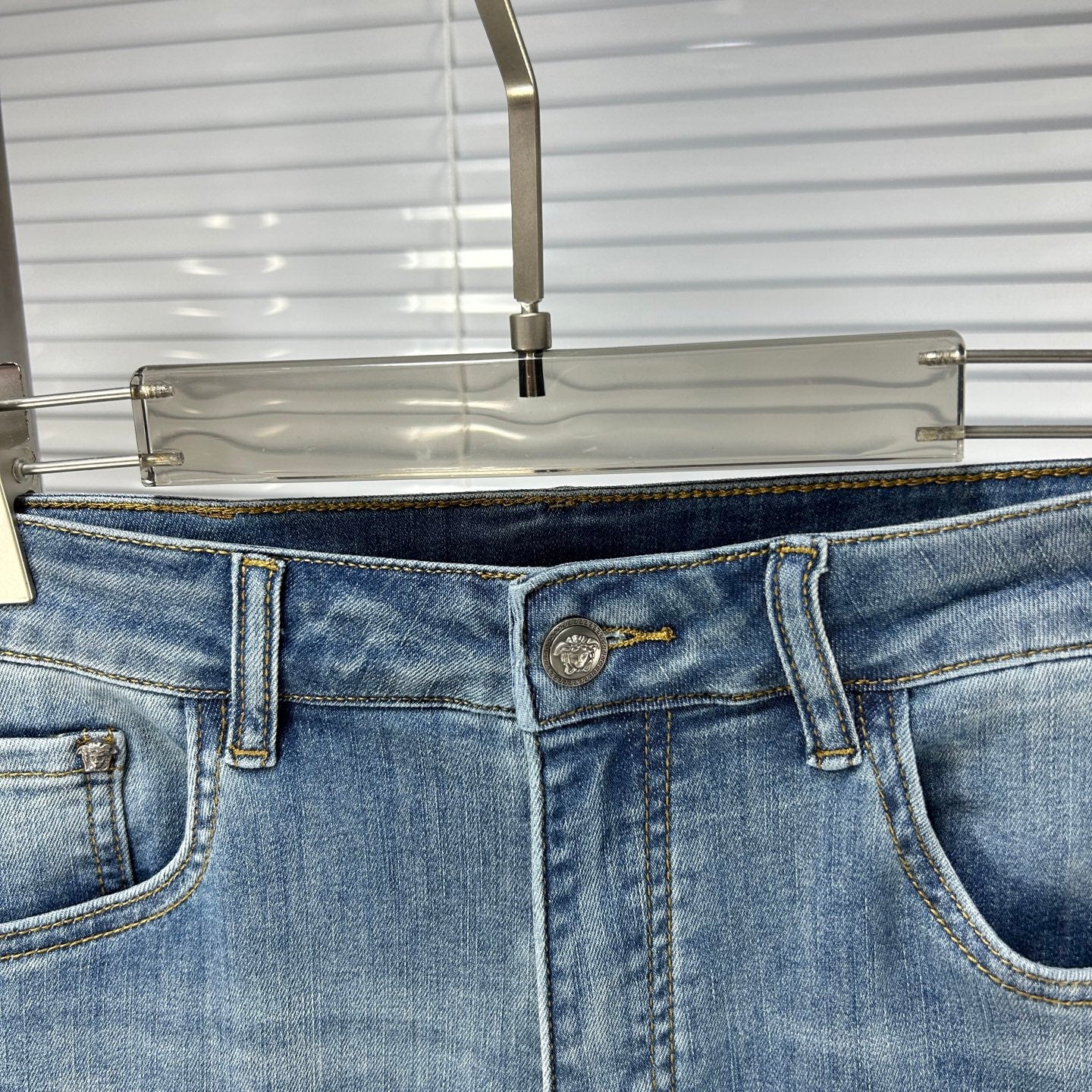 Denim jeans waist with logo button, belt loops, and front pocket stitching
