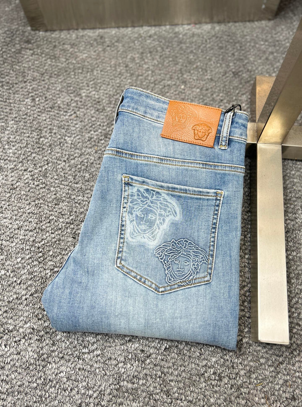 Denim jeans with embroidered back pocket patch and tan leather brand tag