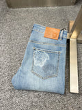Denim jeans with embroidered back pocket patch and tan leather brand tag