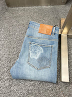 Denim jeans with embroidered back pocket patch and tan leather brand tag