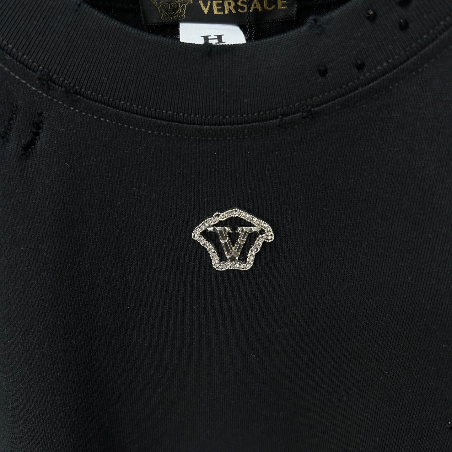 Black crew-neck T-shirt with small gold V emblem on the chest
