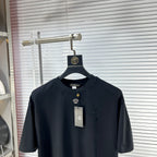 Black crew-neck T-shirt with short sleeves, gold V emblem detail, and neck label
