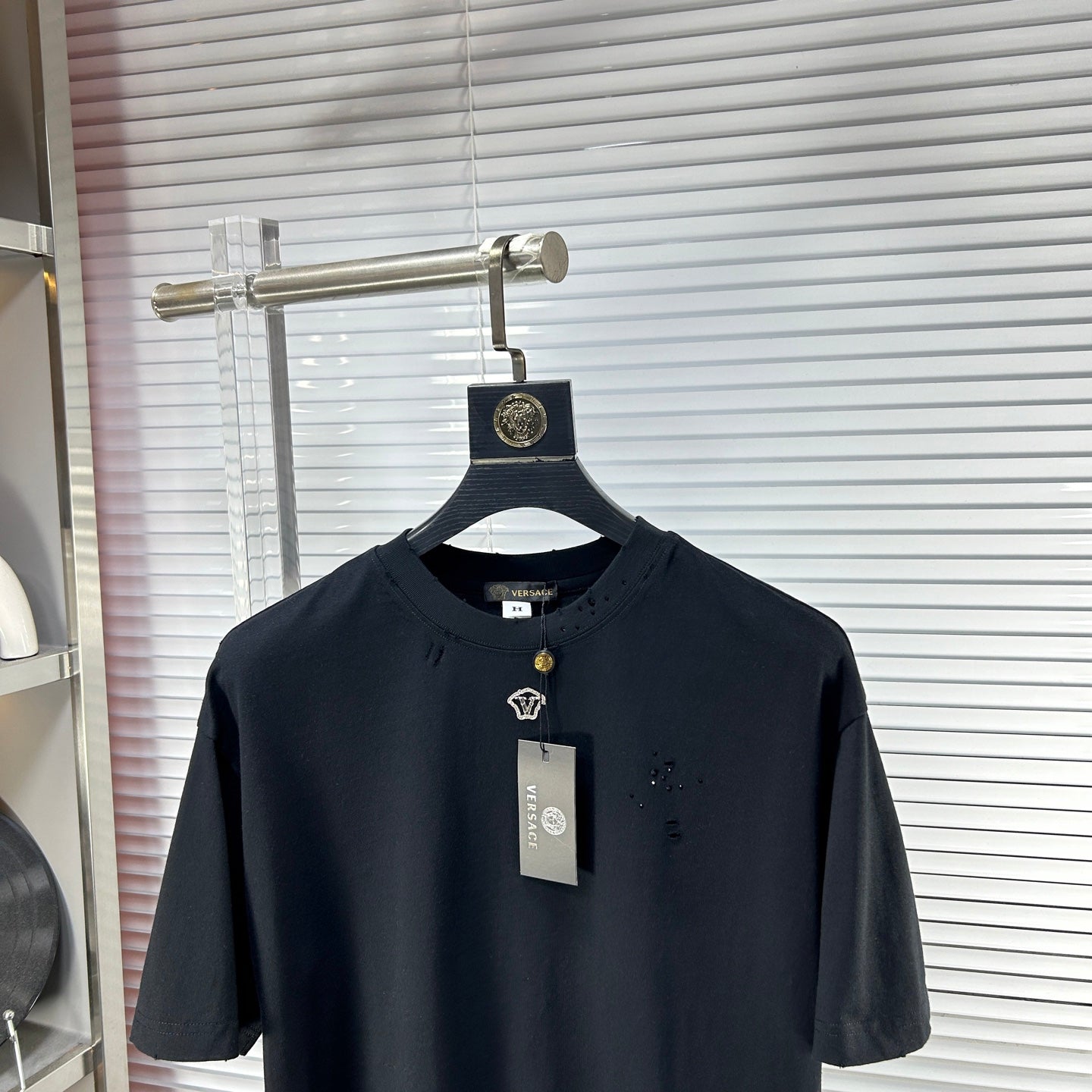 Black crew-neck T-shirt with short sleeves, gold V emblem detail, and neck label
