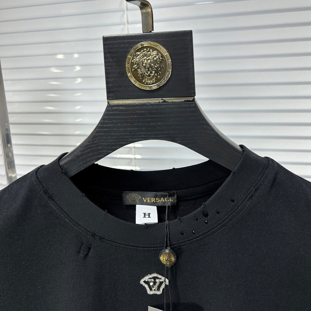 Black crew-neck T-shirt collar with gold pendant charm and small V logo patch