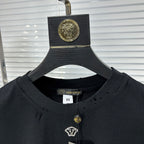 Black crew-neck T-shirt collar with gold pendant charm and small V logo patch