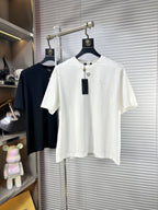 White crew-neck T-shirt with short sleeves, small gold V emblem, and speckle detailing