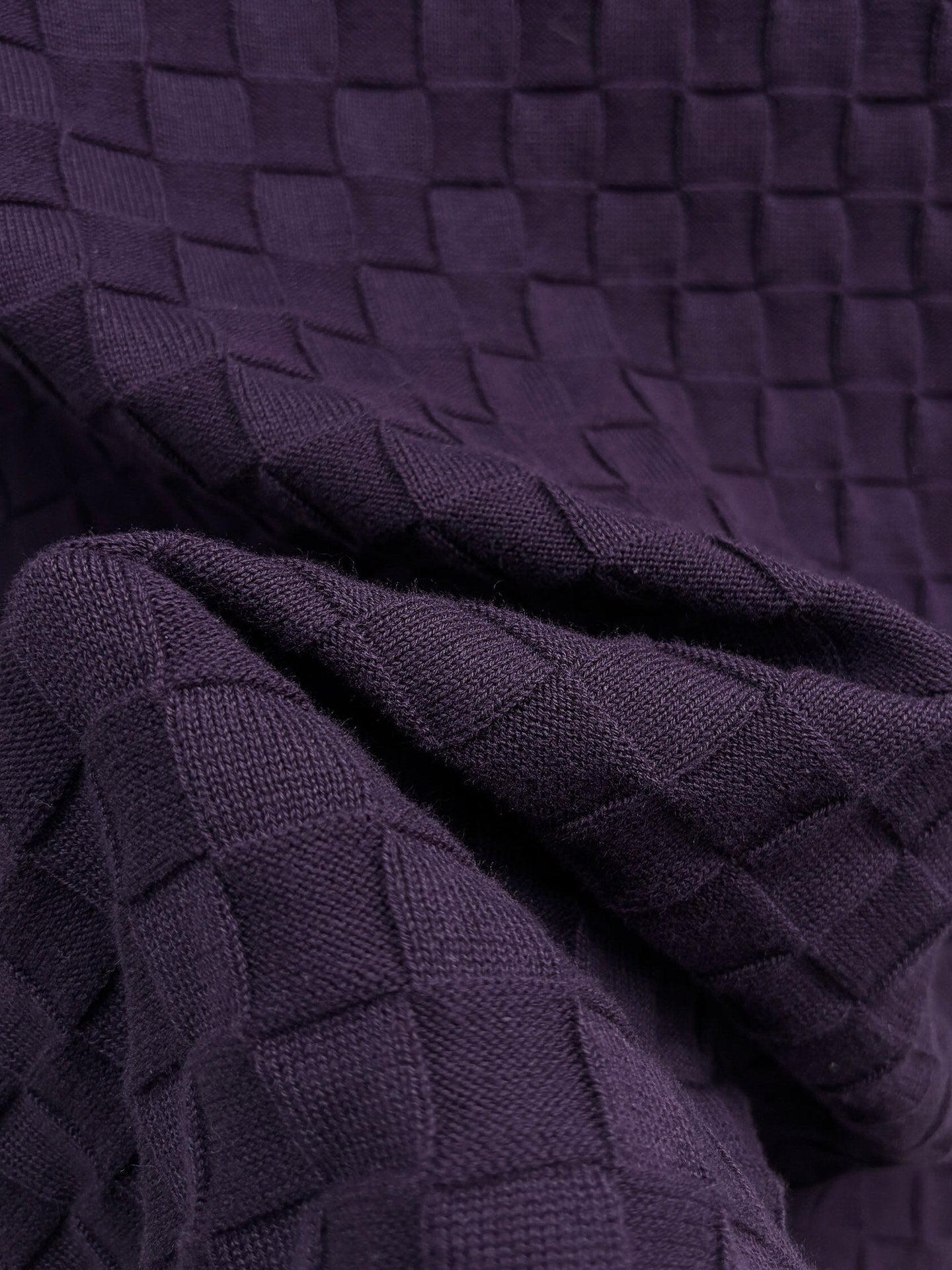 Purple textured knit T-shirt fabric close-up with woven square pattern