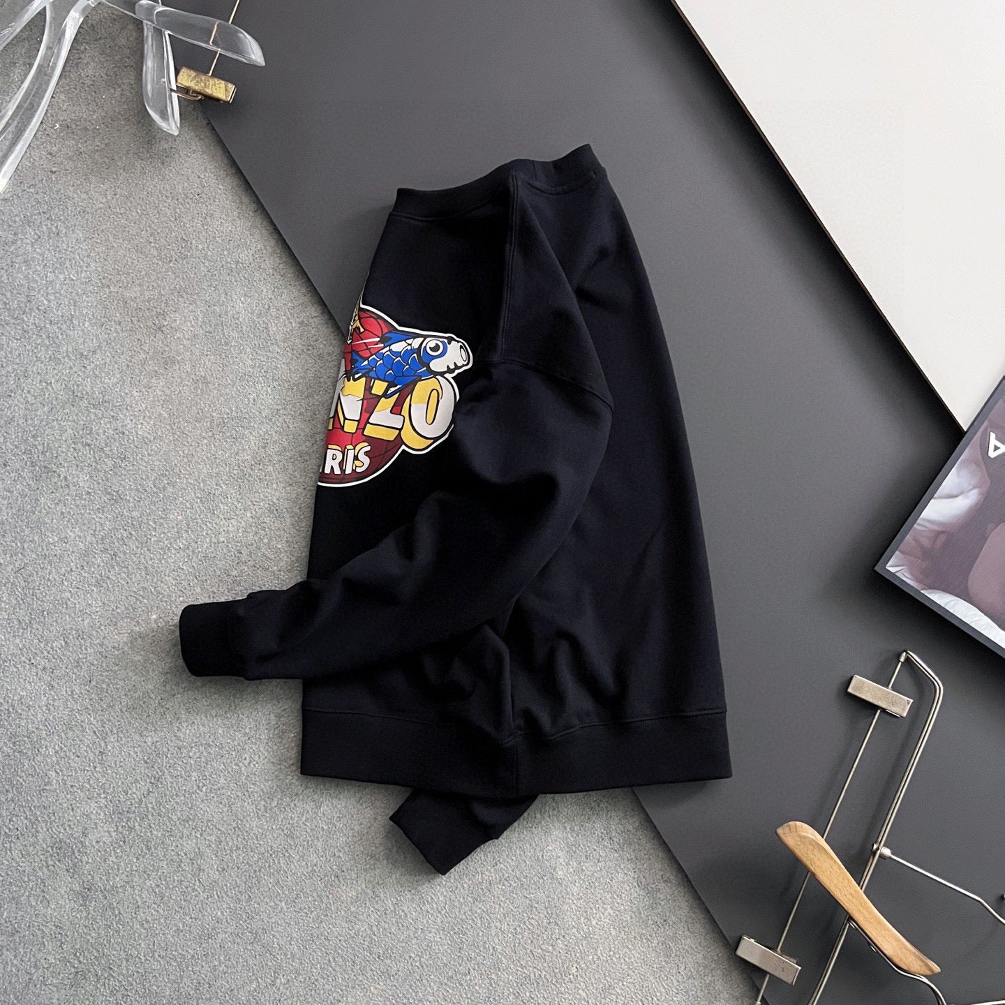 Black sweatshirt with "KENZO PARIS" graphic, folded on a hanger