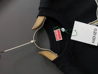 Black sweatshirt sleeve with green and white brand tag near the hem