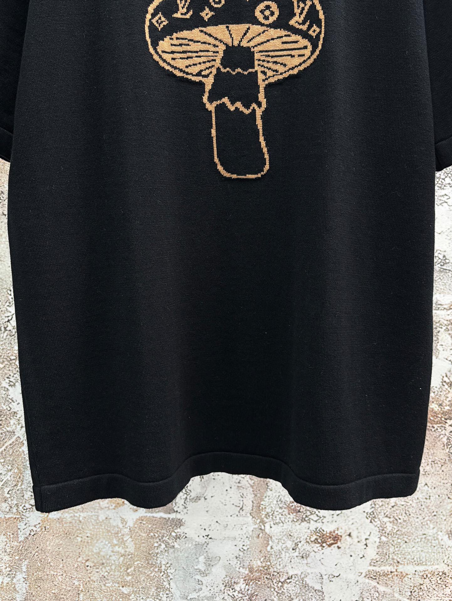 Black short-sleeve T-shirt hem with gold embroidered mushroom emblem graphic
