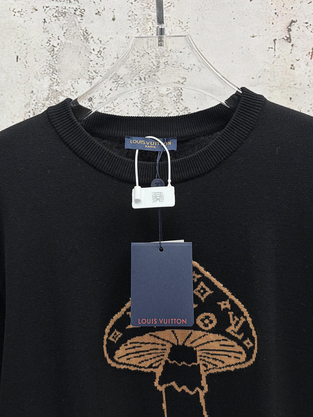 Black T-shirt with gold embroidered mushroom emblem and hanging garment tags
