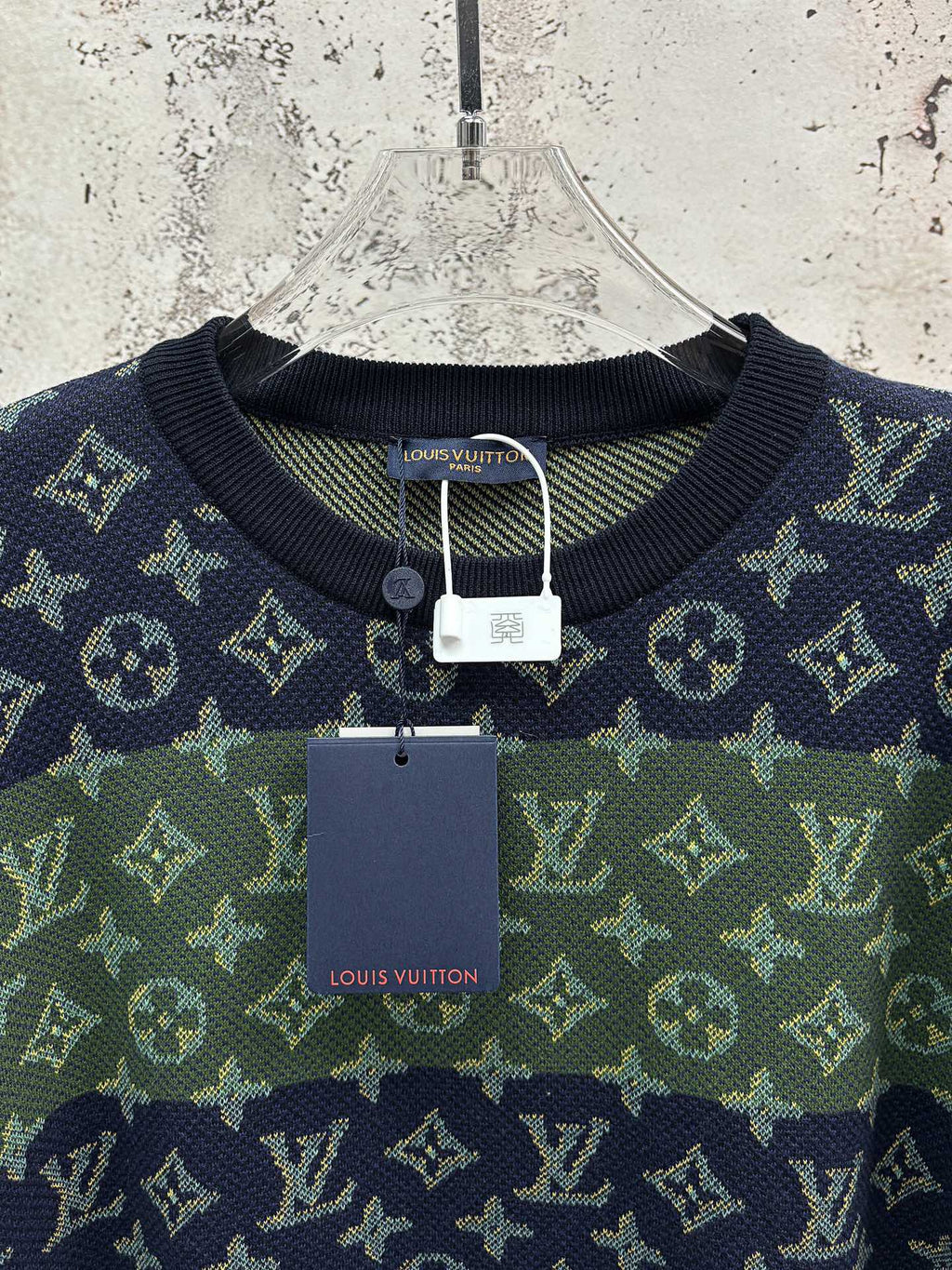 Crewneck short-sleeve shirt hanging on hanger with navy and green monogram pattern