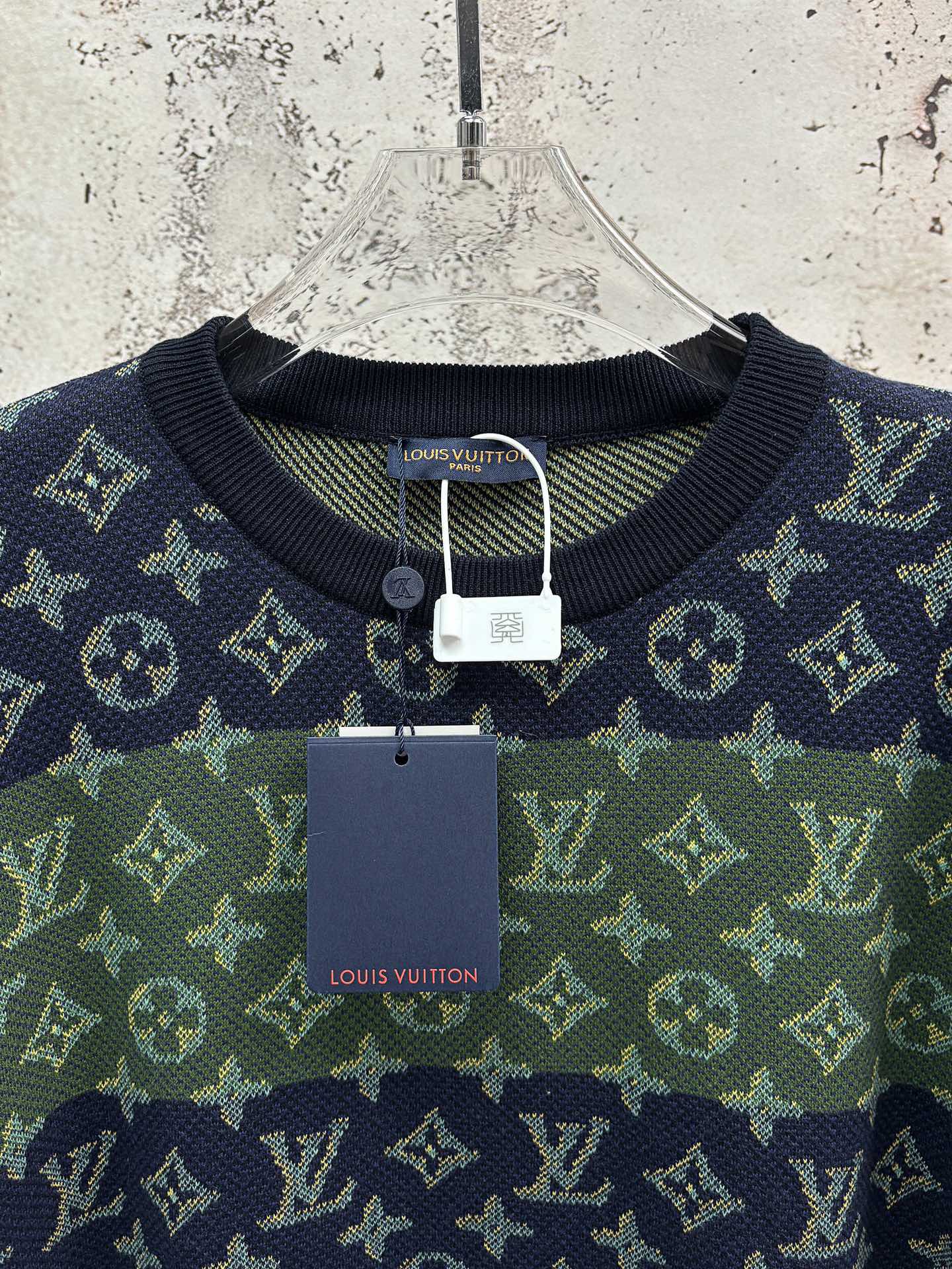 Crewneck short-sleeve shirt hanging on hanger with navy and green monogram pattern