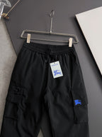 Black cargo pants with elastic waist, drawstring, side pockets and blue patch on thigh