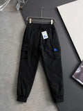 Black cargo pants with elastic waistband, drawstring, side pockets, and blue patch detail