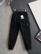Black cargo pants with elastic waistband, drawstring, side pockets, and blue patch detail