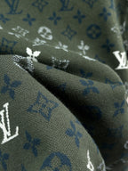 Dark green monogram fabric close-up with blue-and-white printed symbols