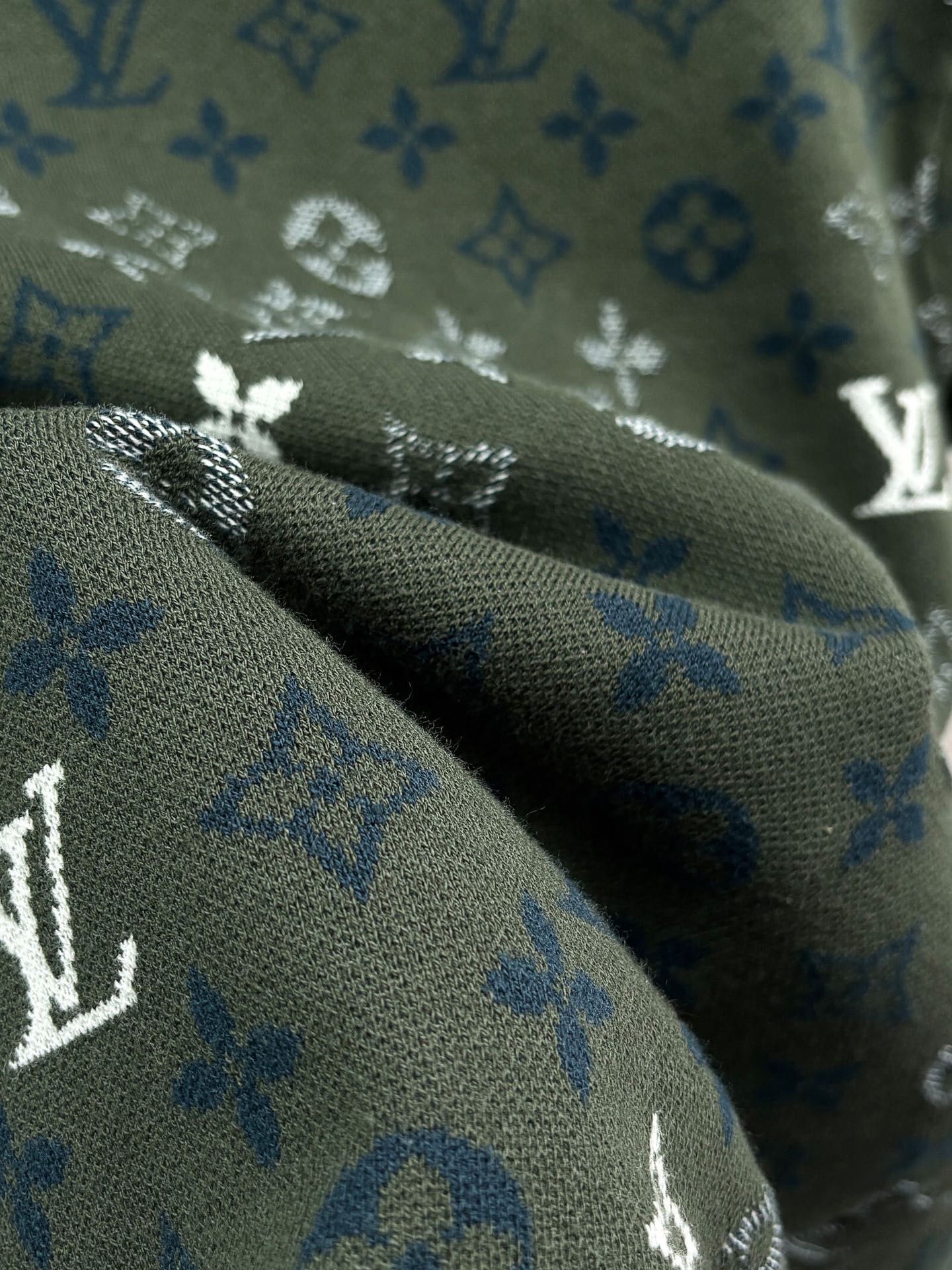 Dark green monogram fabric close-up with blue-and-white printed symbols
