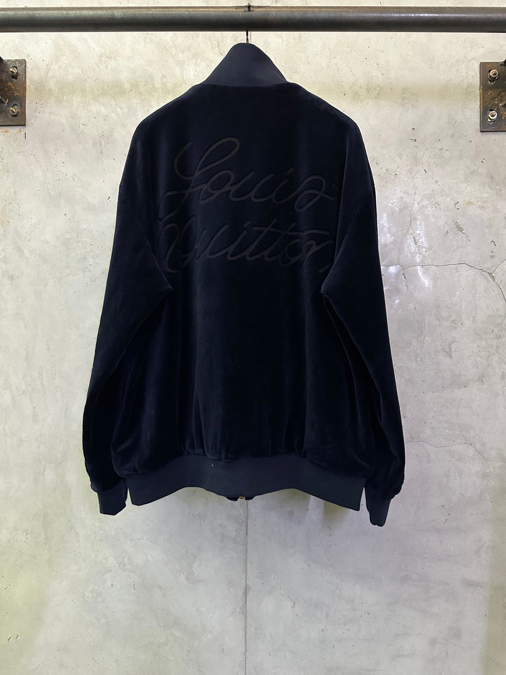 Dark navy zip-up jacket, back view with cursive logo embroidery