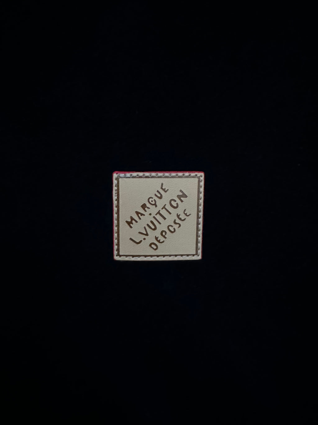 Garment label patch reading "Marque Vuitton" and "Depute"