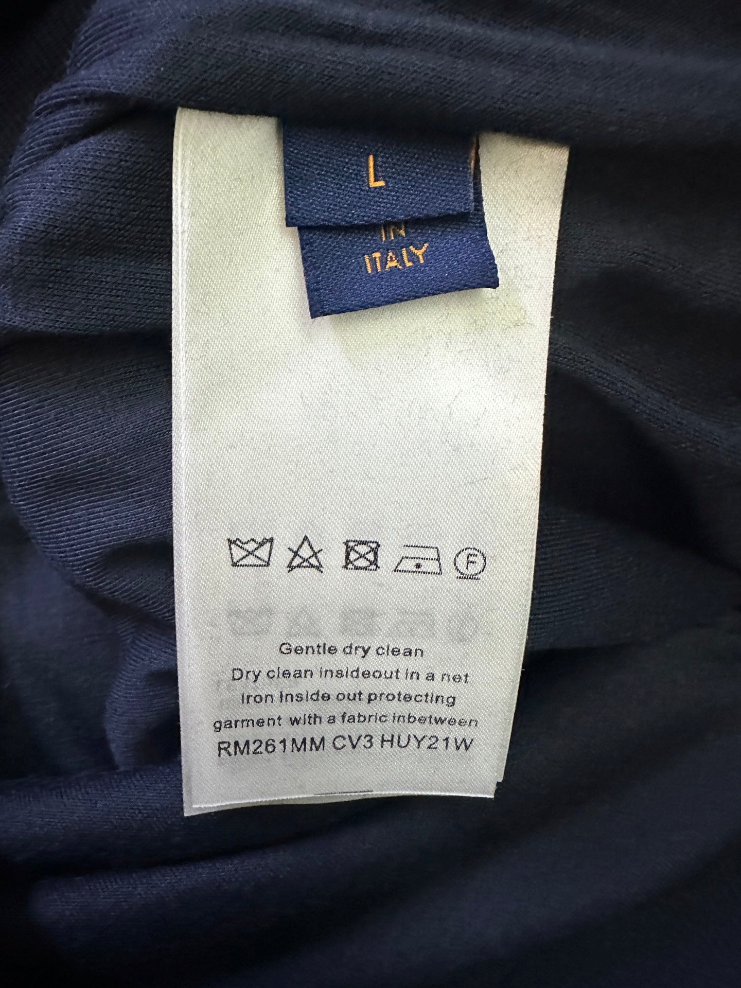 Clothing care label with "Dry clean only" and protectant symbols on fabric tag