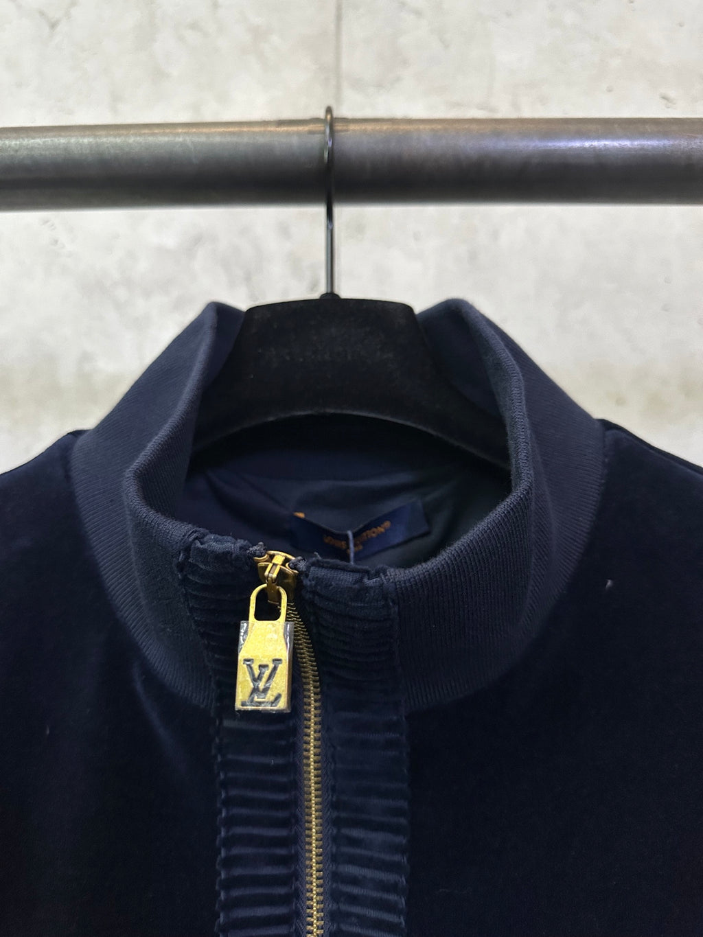 Dark navy jacket collar and zipper close-up with gold zipper pull and LV emblem