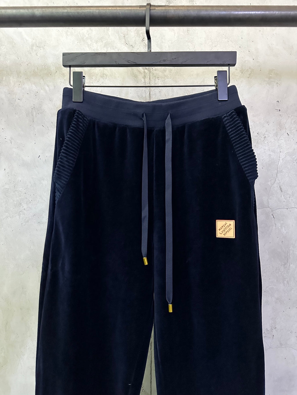 Navy pants with textured side panels, drawstring ties, and logo patch
